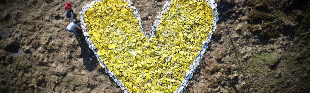 A view from above of a yellow heart made of stones on a hillside.