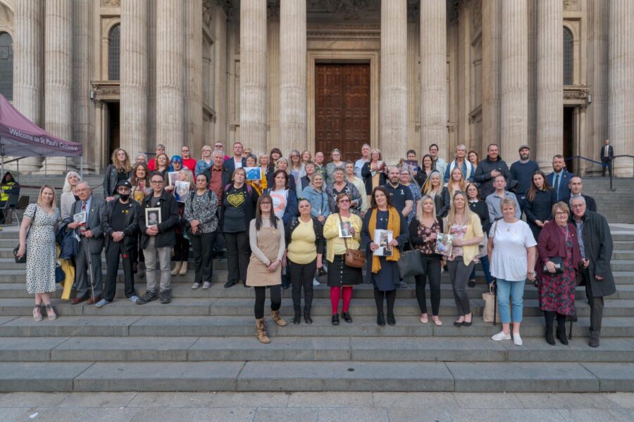 A large group of people stand for a group photo on the steps of a building.