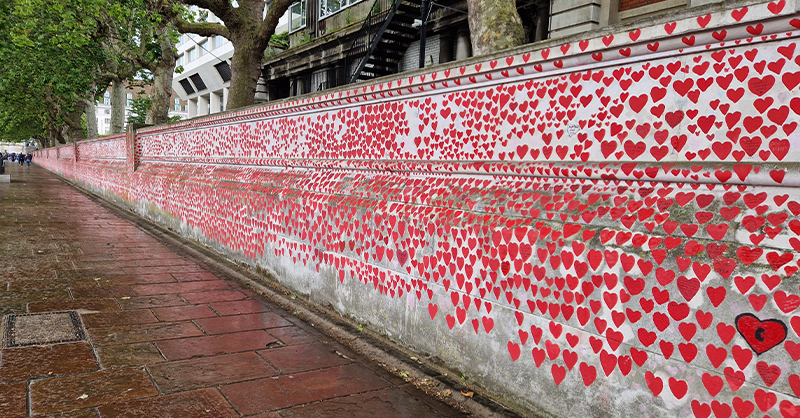 The National Covid Memorial Wall on a wet day. The wall is covered with many small red hearts.