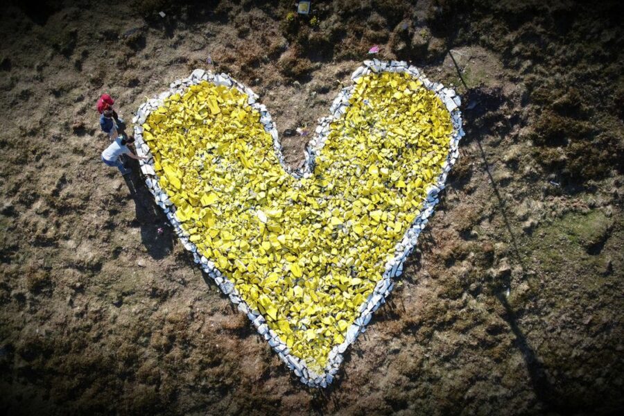 A view from above of a yellow heart made of stones on a hillside.